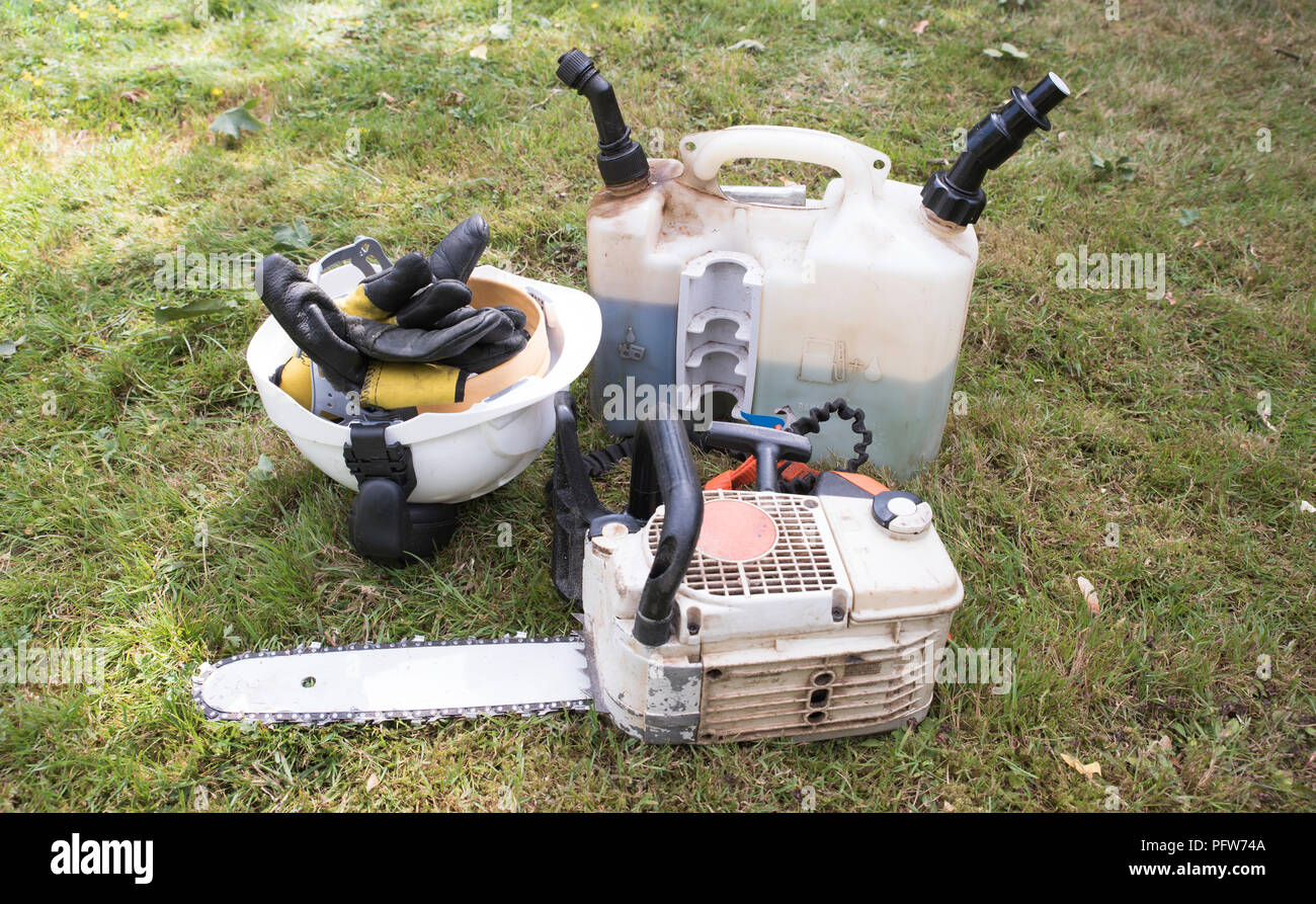 Chainsaw ready for use after re filling with oil and fuel.Safety gear is near by. Stock Photo