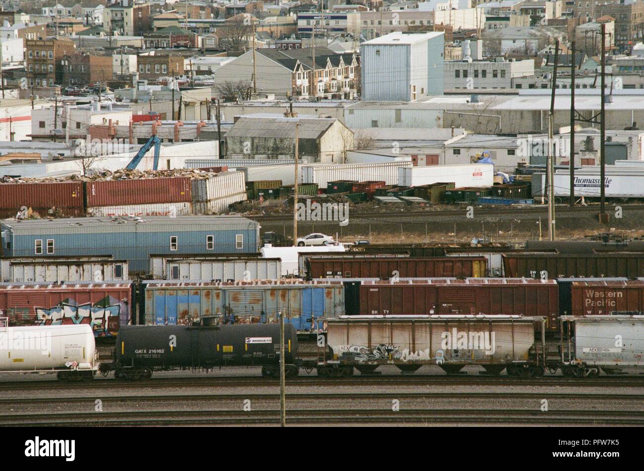 Aerial view, close-up of row homes bordering on a rail yard, with freight trains visible, in an industrial portion of Newark, New Jersey, March 18, 2018. () Stock Photo