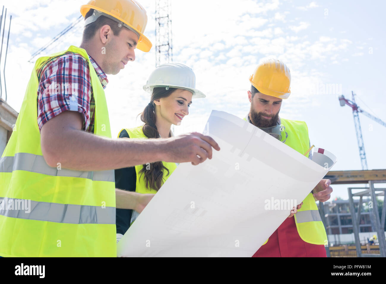 Experienced architect analyzing a blueprint on the construction site Stock Photo
