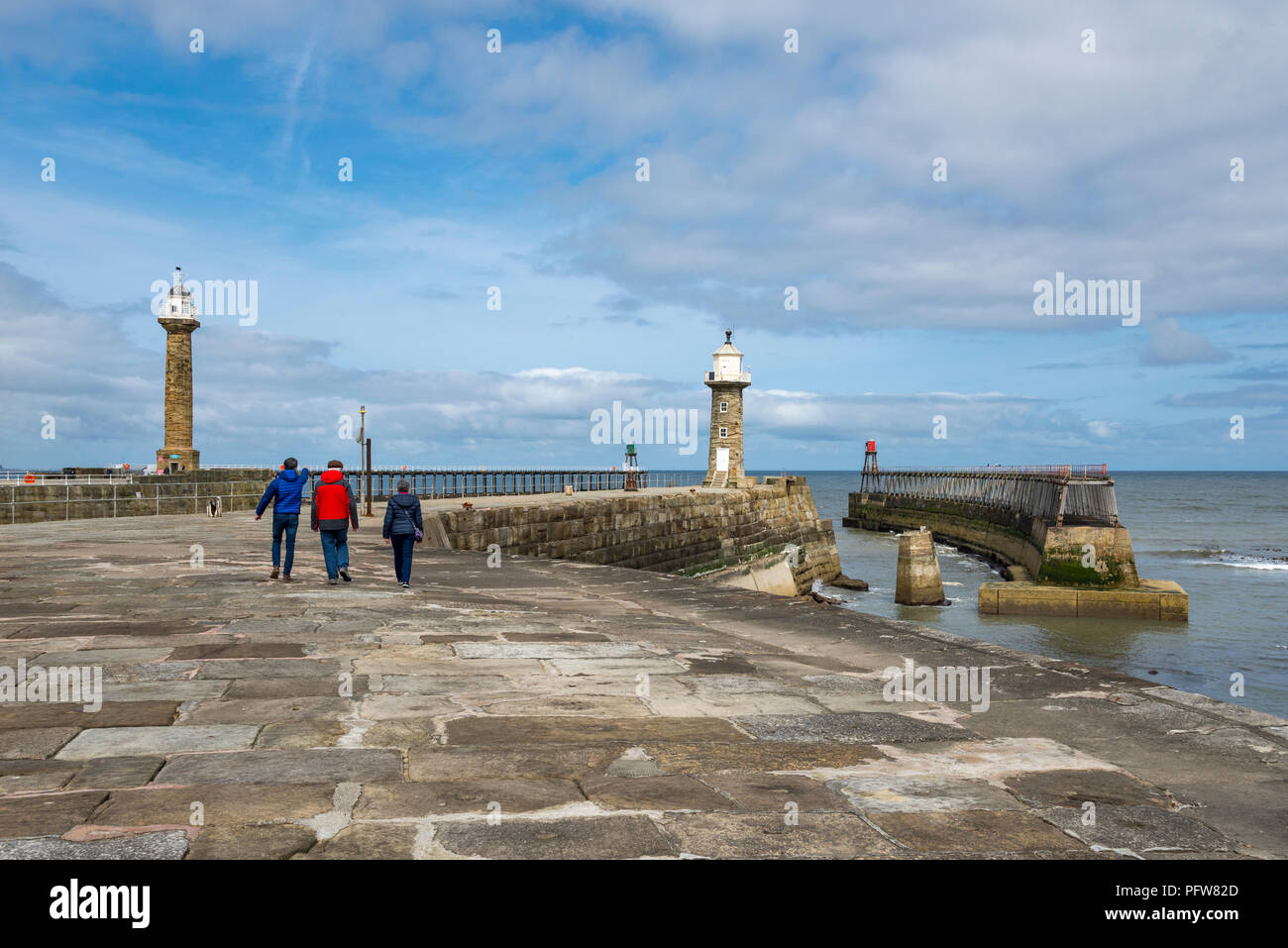 Family taking a stroll along the East Pier at Whitby on the coast of North Yorkshire, England. Stock Photo