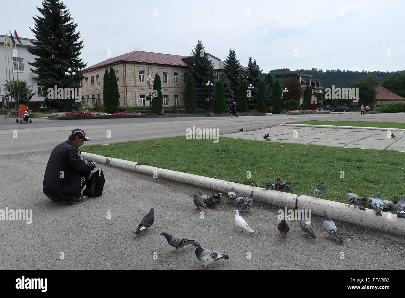 Man feeding pigeons in the city of Chortkiv which was once home to a large Jewish community and was annihilated, brutally, by the Germans during the Second World War in Ternopil Oblast (province) in western Ukraine. Stock Photo