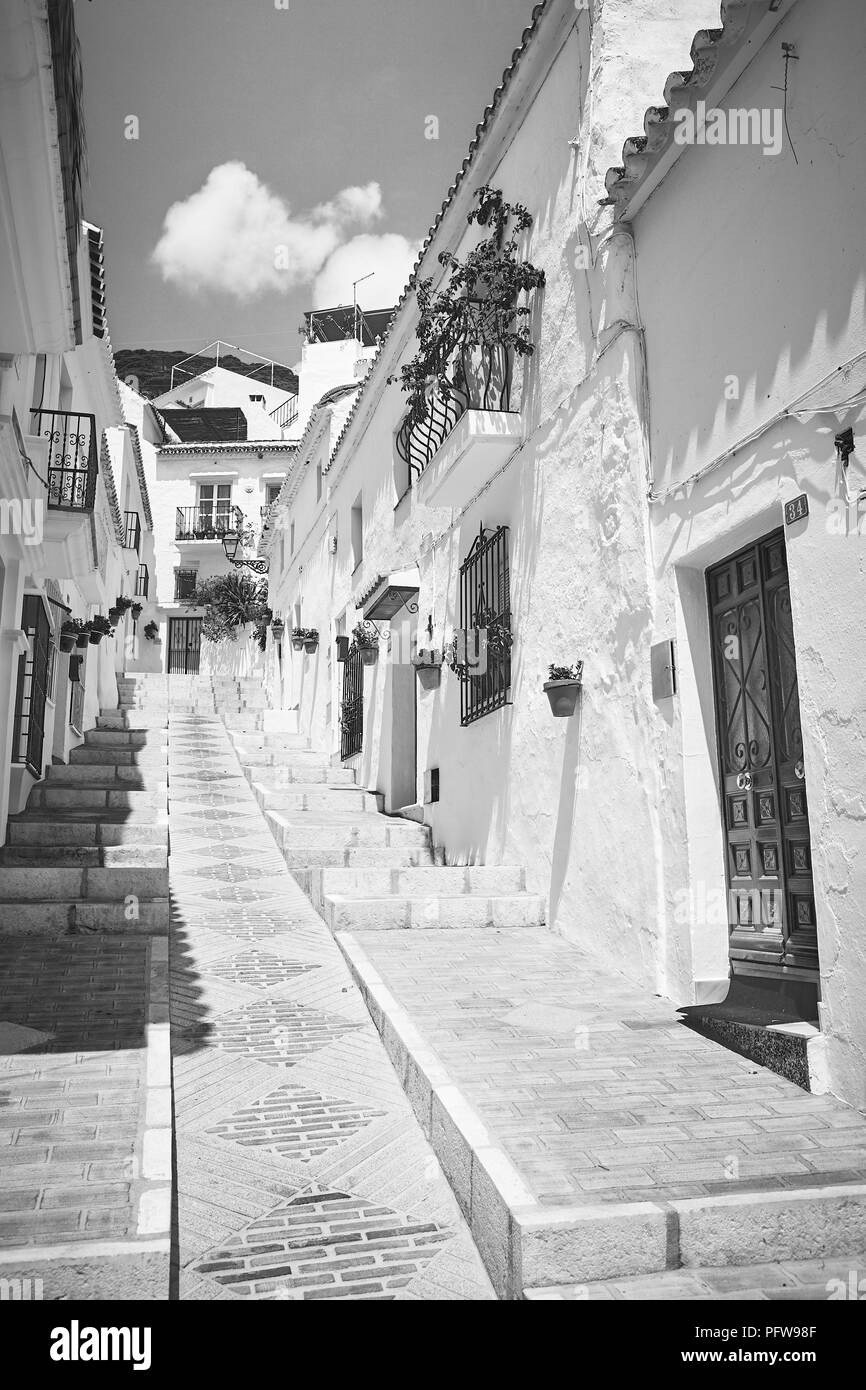Black and white photo looking up a steep narrow Spanish street of white walled houses in Mijas, Andalusia in southern Spain Stock Photo