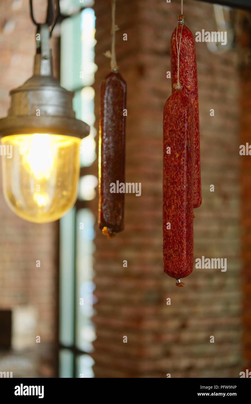 Smoked  sausagees hanging on a hook under the ceiling. Photo with shallow depth of field. Stock Photo