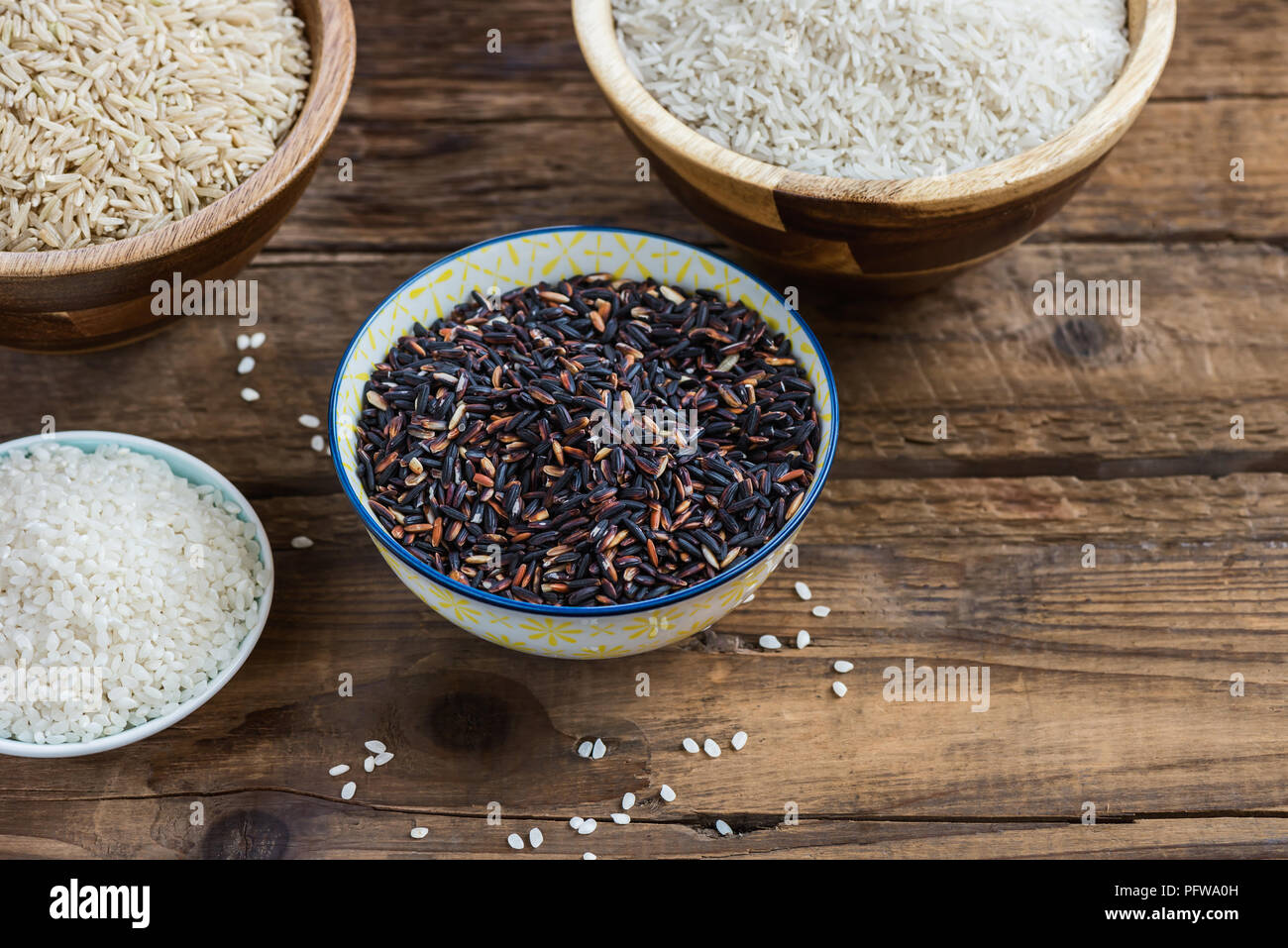 Different types of rice in wooden bowls such as basmati, brown and ...