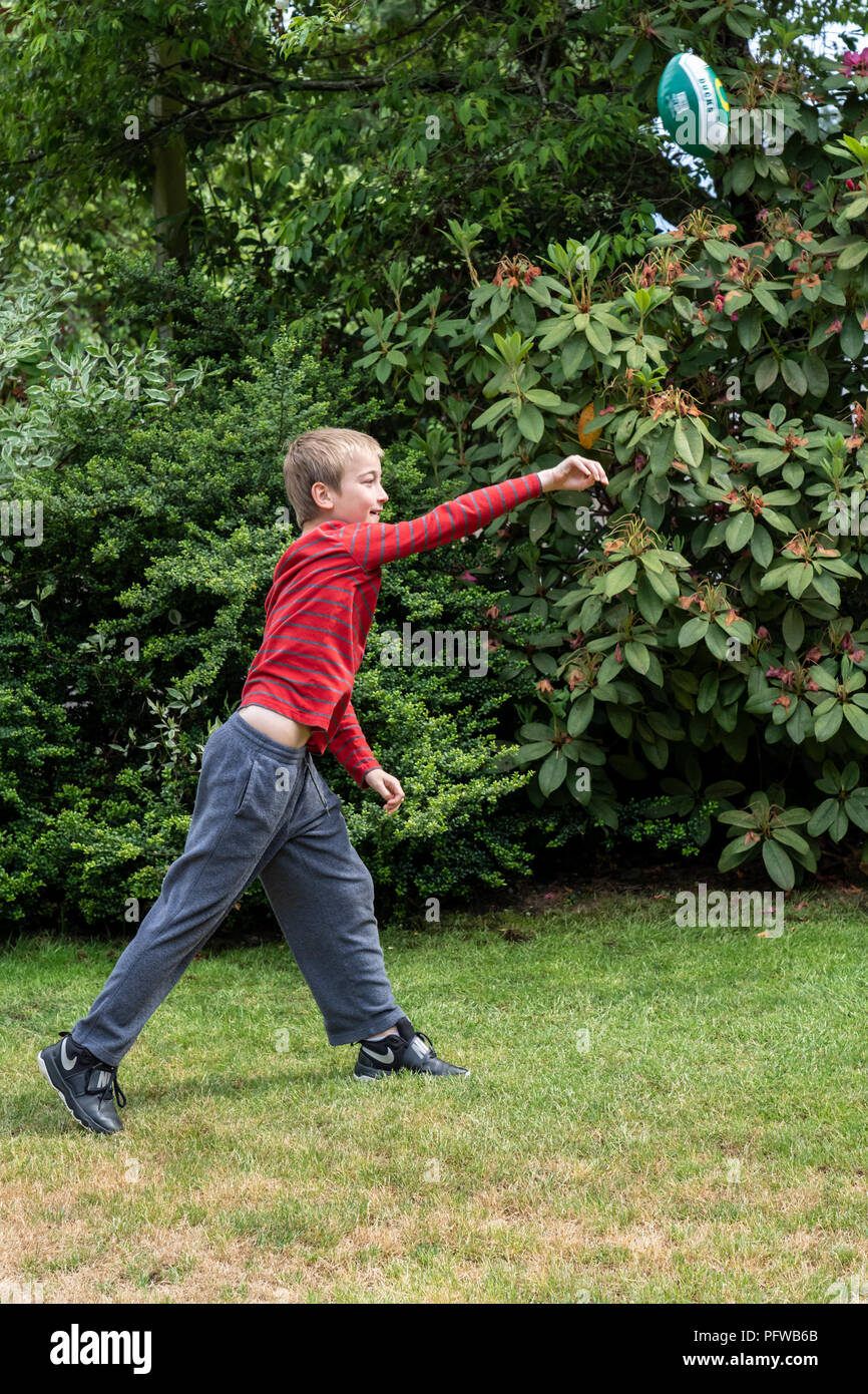 10 year old boy throwing a football on his lawn Stock Photo