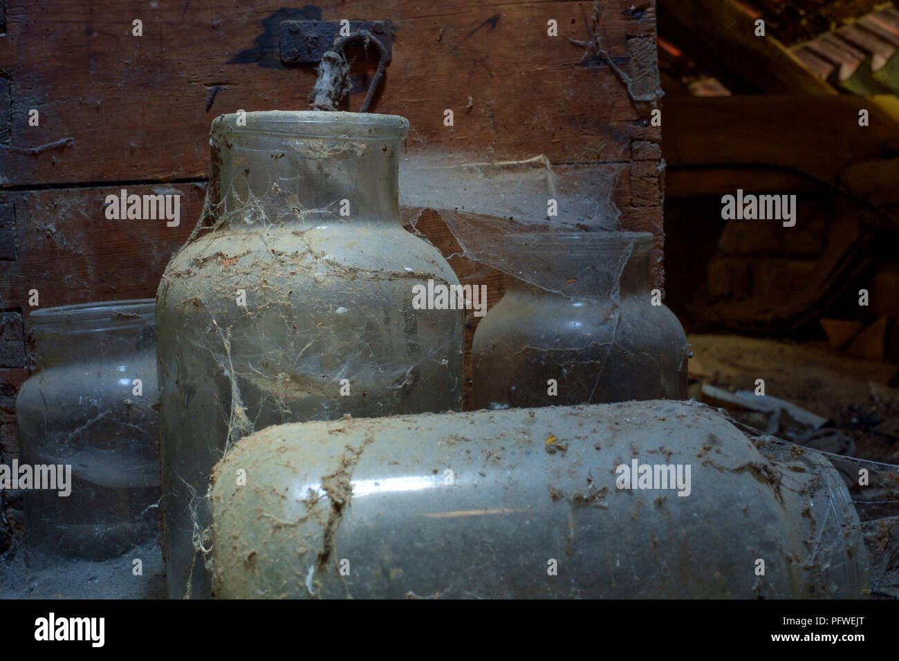 old glass jars and wooden box covered in dust and cobwebs laying undisturbed and forgotten in an old farmhouse attic zala county hungary Stock Photo