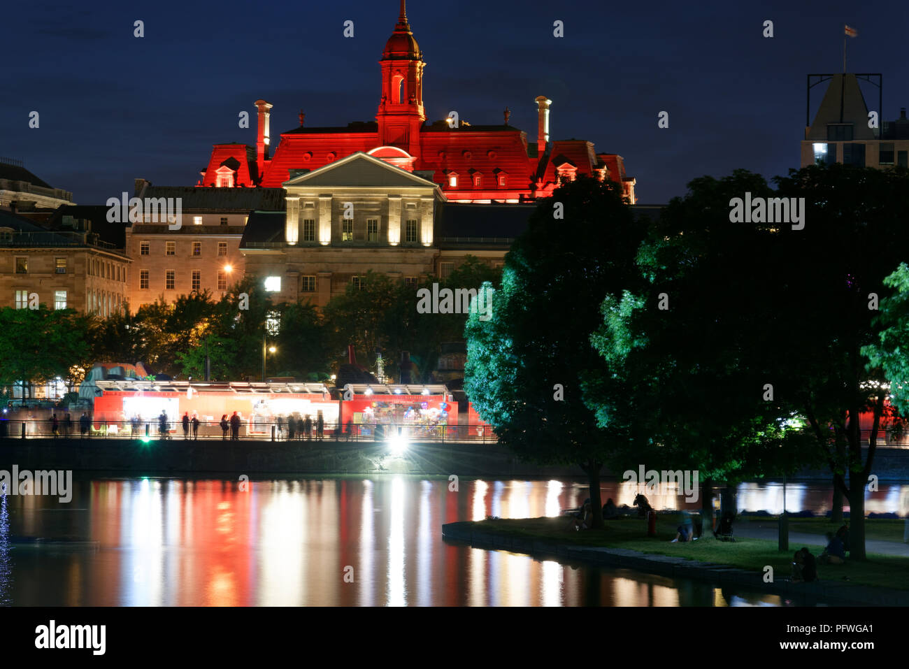 The Hotel de Ville and the Maché Bonsecours building at night, with lights on the water of Bassin Bonsecours Stock Photo