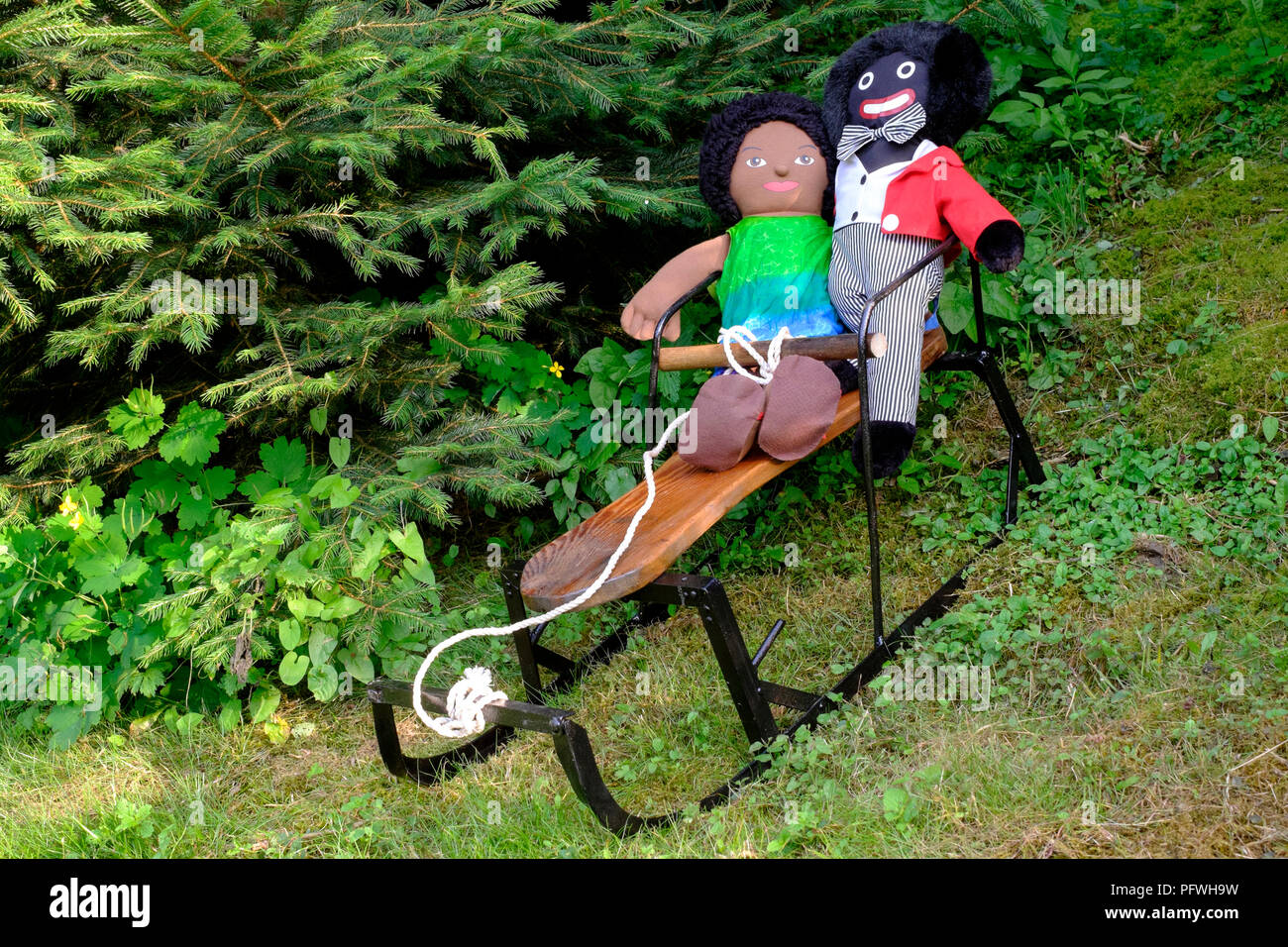 golliwog and brown doll soft toys sitting on small sledge  with christmas trees behind zala county hungary Stock Photo