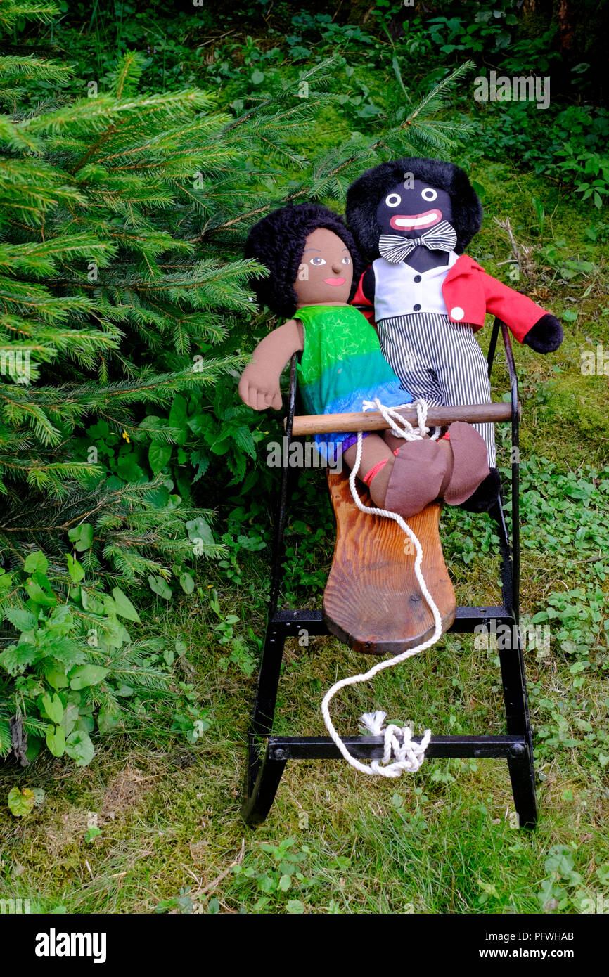 golliwog and brown doll soft toys sitting on small sledge  with christmas trees behind zala county hungary Stock Photo