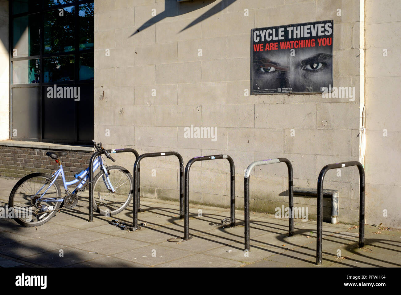 bicycle locked to a stand below a poster warning of cycle thieves portsmouth england uk Stock Photo