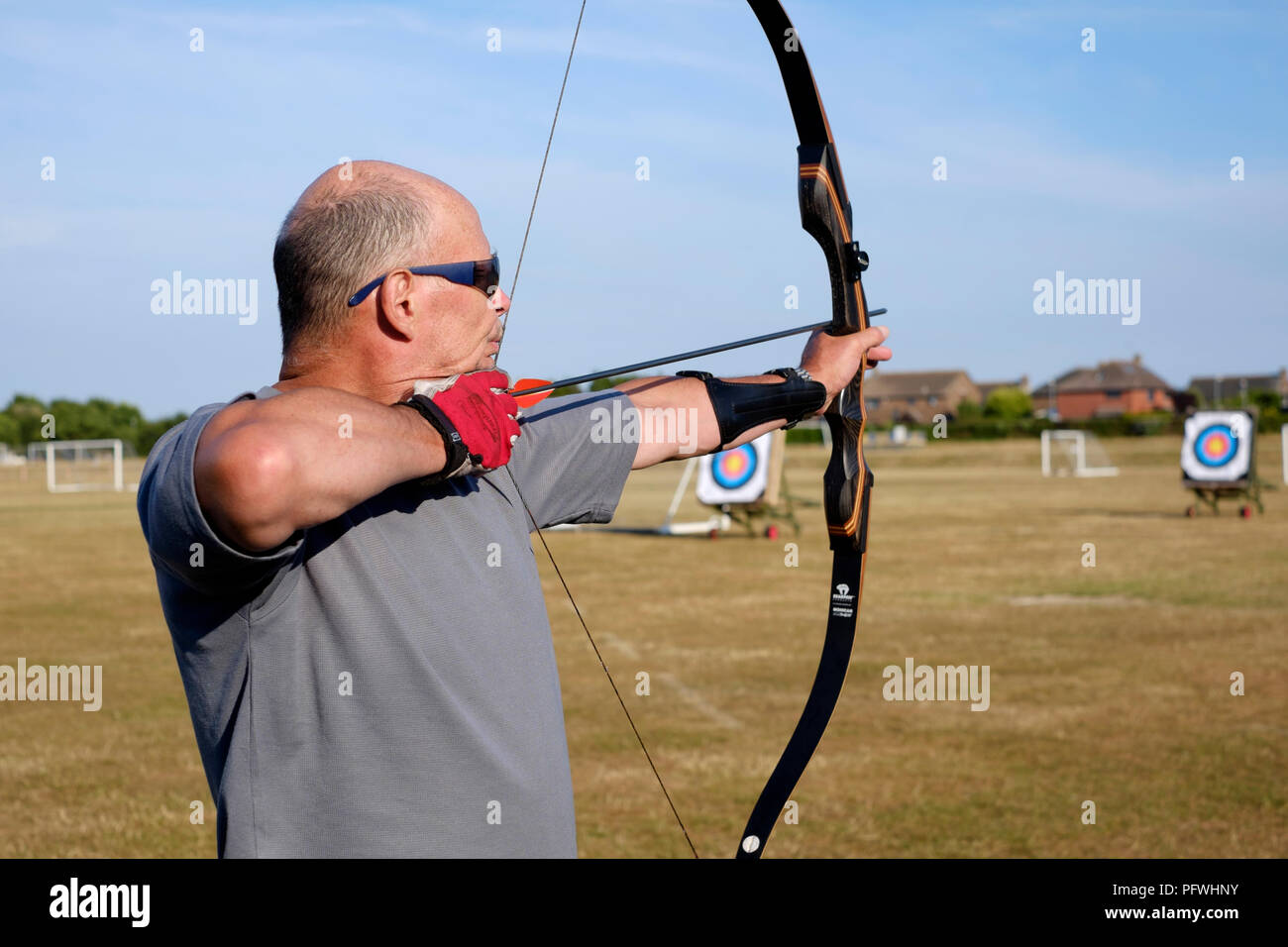 male archer using a bow for target practice at an archery club