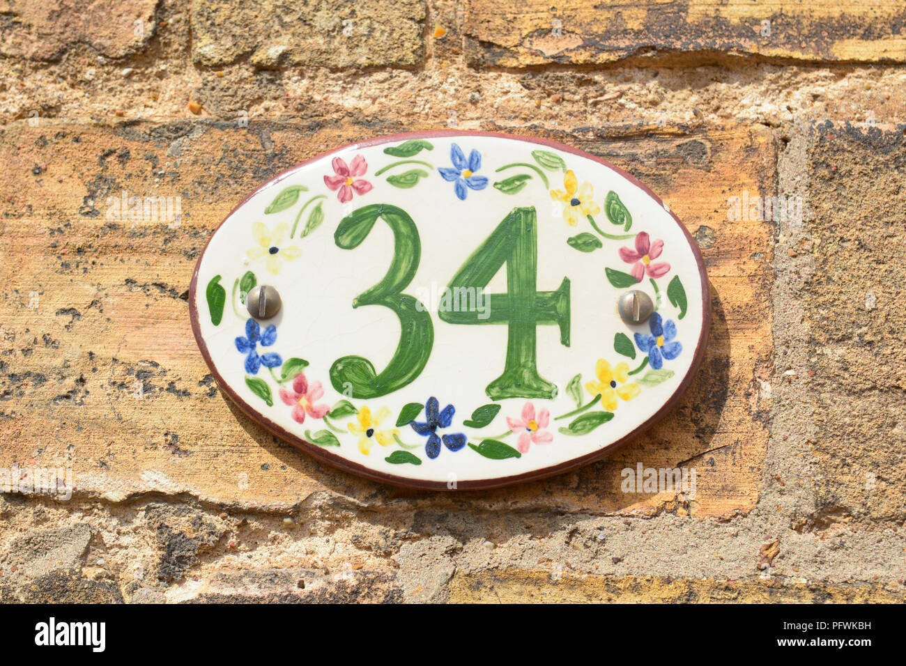House number 34 sign on ceramic tile with painted flowers Stock Photo
