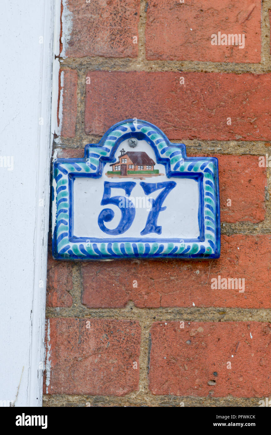 House number 57 sign - ceramic tile on red brick wall Stock Photo