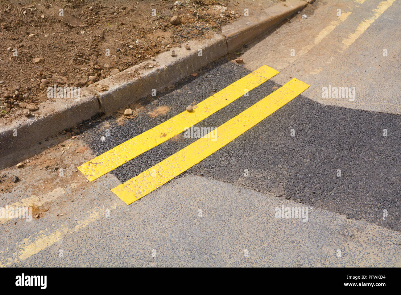 Tiny section of newly painted double yellow lines on road next to kerb