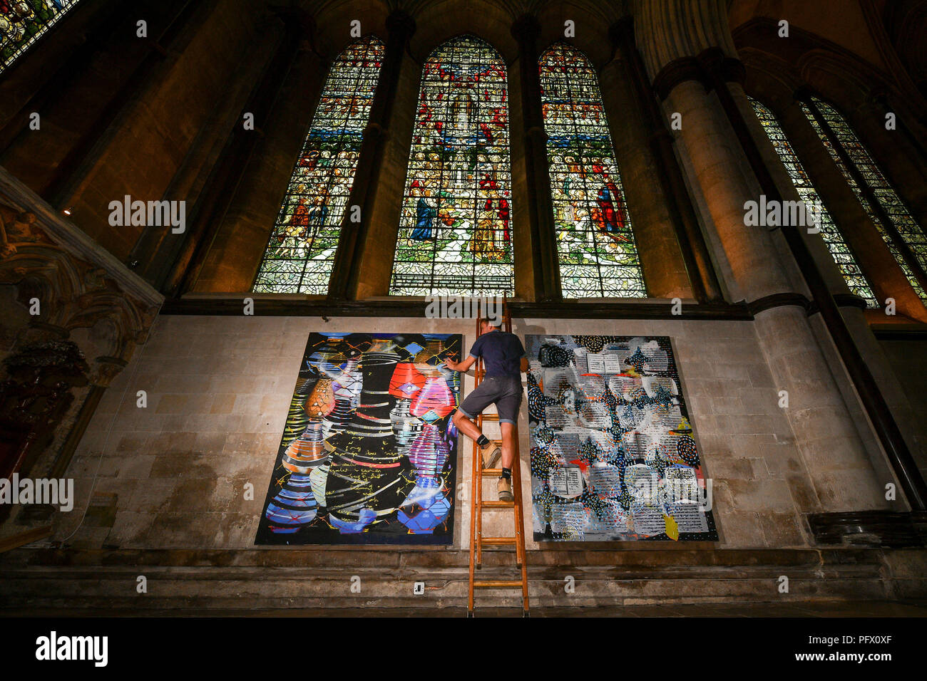 Finishing touches are applied to pictures being hung in the Morning Chapel at Salisbury Cathedral in preparation for an exhibition by Professor Stephen Farthing. The works, The Miracle Paintings 2011-2018, took eight years to complete. Stock Photo