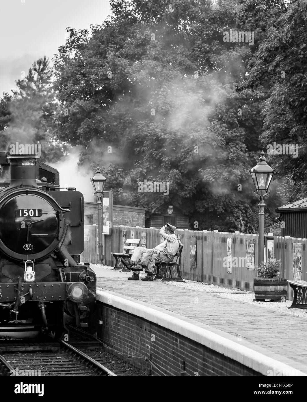 Black & white UK steam engine crew taking a quick break outside the cab, Severn Valley Railway Arley station. Front view of loco 1501 steaming. Stock Photo