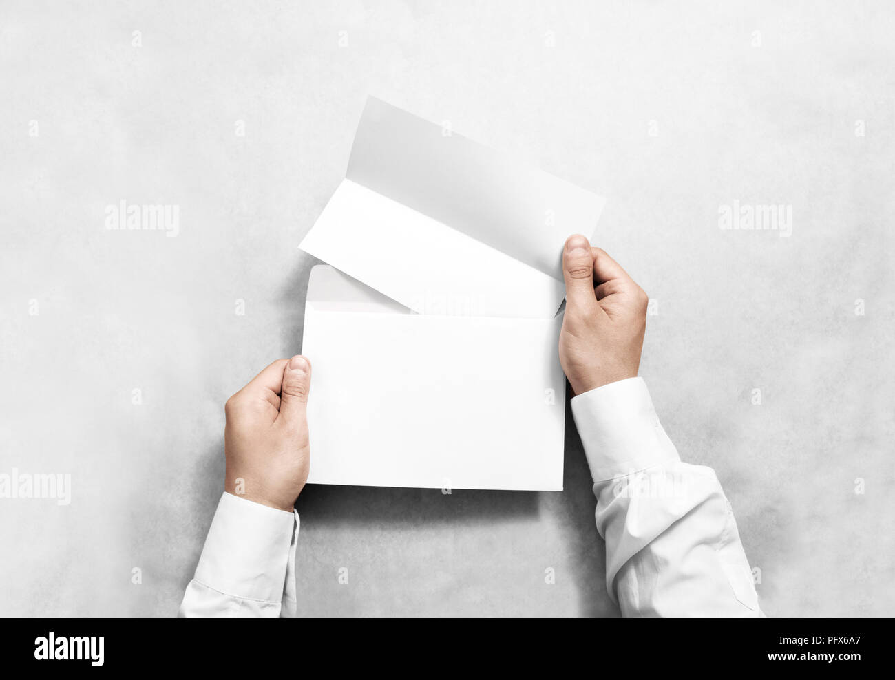 Hand holding white blank envelope and folded leaflet mockup, isolated. Arm hold empty brochure template mock up. Greeting card flyer design. Invitatio Stock Photo