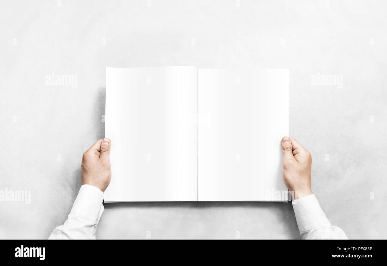 Hand opening white journal with blank pages mockup. Arm in shirt holding clear magazine template mock up. Stock Photo