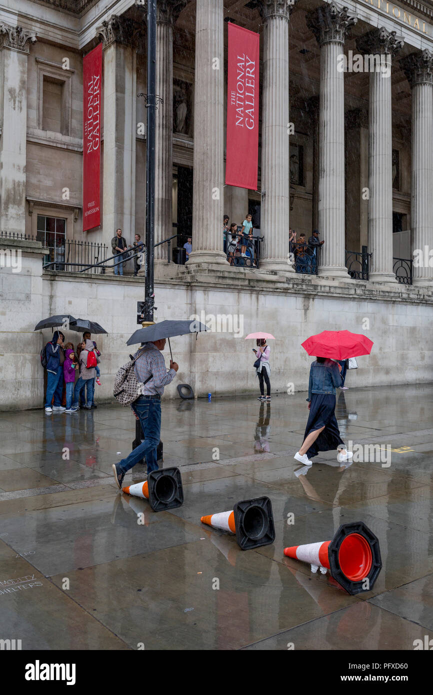 A family shelters beneath umbrellas during a sudden downpour outside