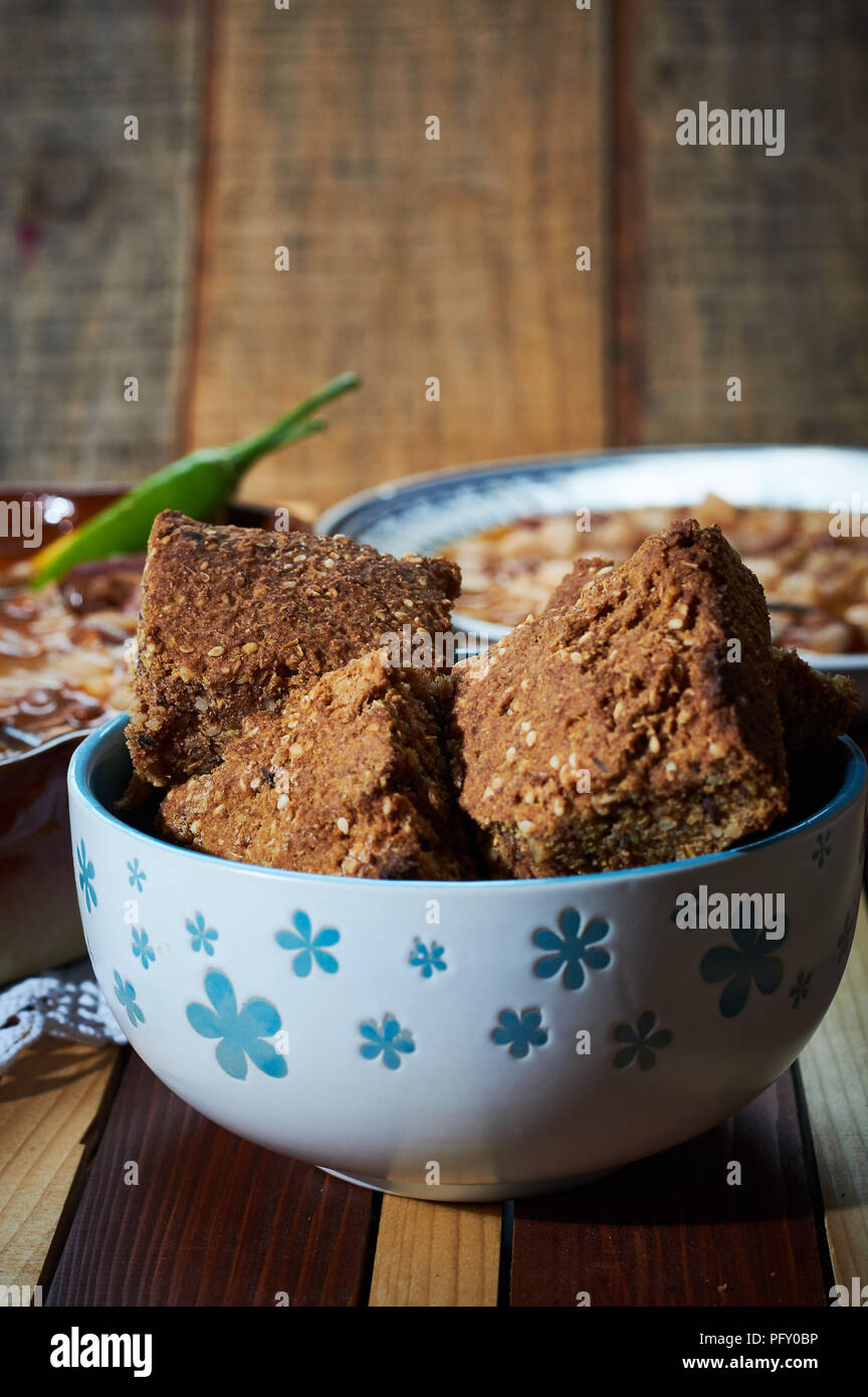 Spelta bread in bowl with Beans with smoked pork on plate in the bacground Stock Photo