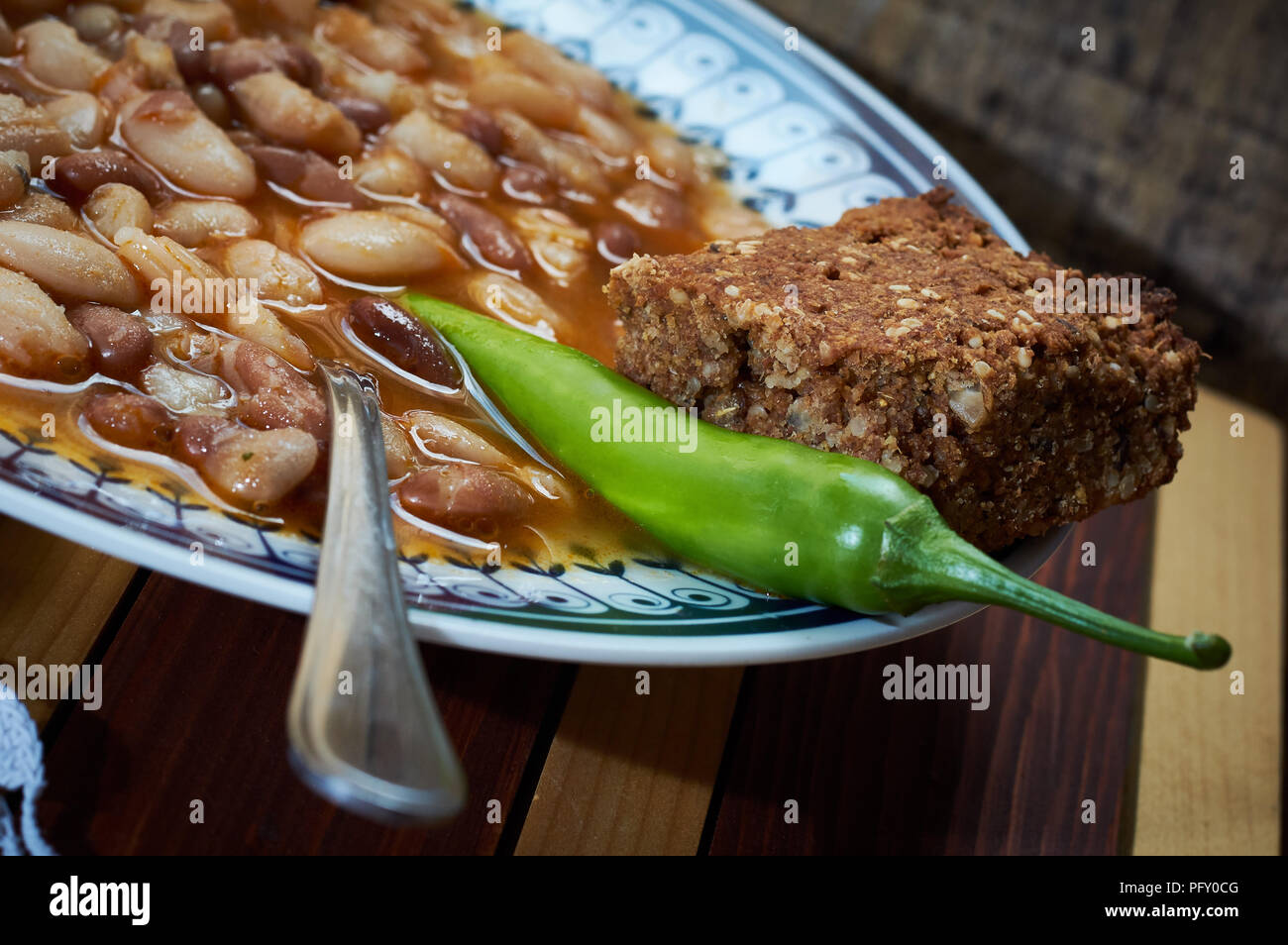 Beans with smoked pork on dinner plate with spelta bread and pepper on the plate Stock Photo