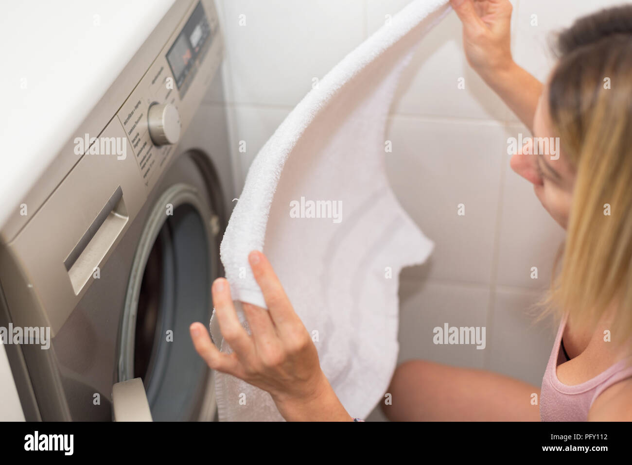 Young blonde woman doing laundry, shallow deep of field. Stock Photo