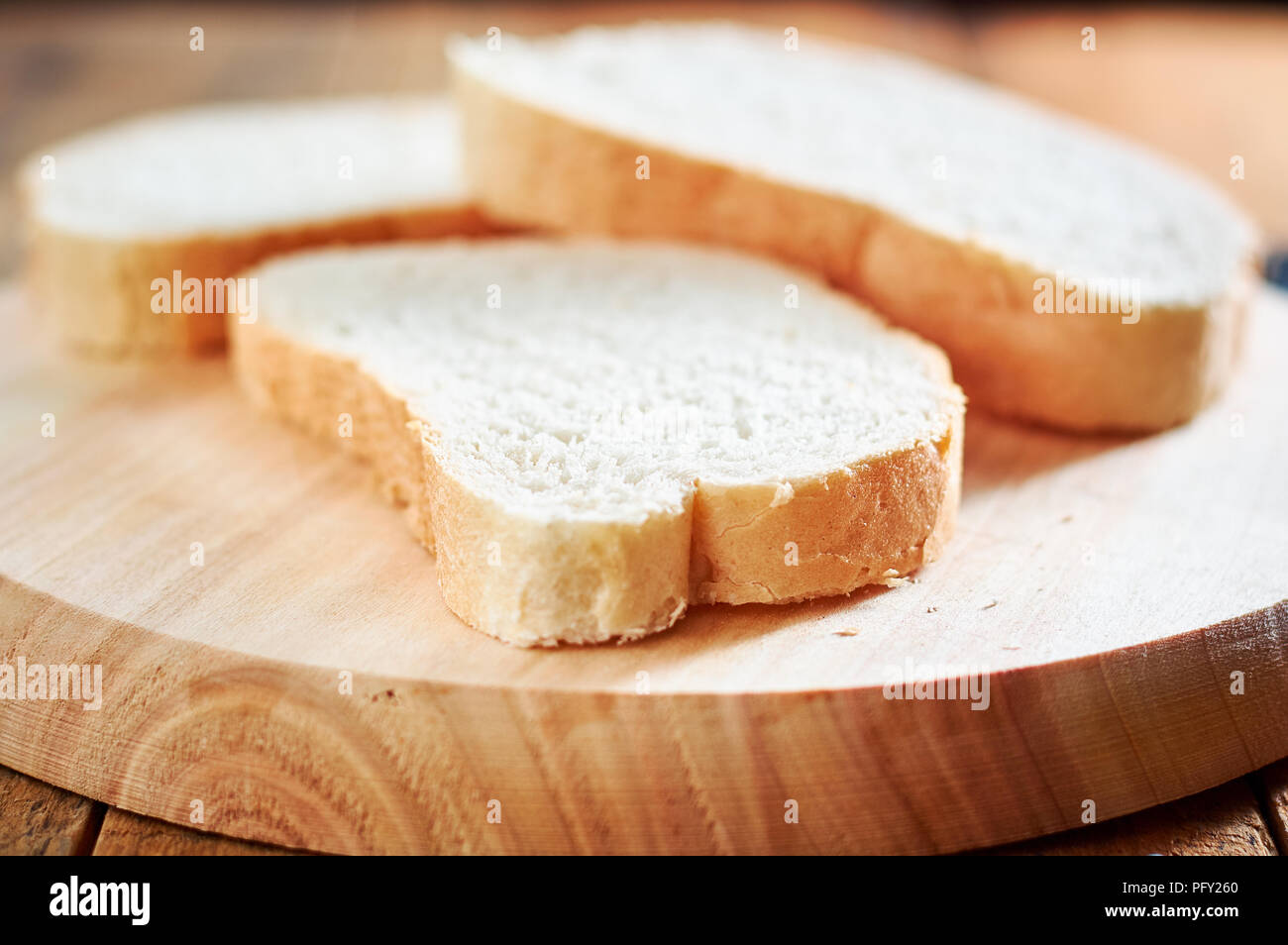 Fresh slices of bread on wooden plate. with shallow depth of field Stock Photo