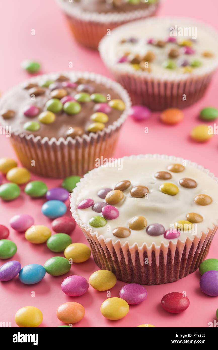 Sweet cupcakes with candies on pink background. Stock Photo
