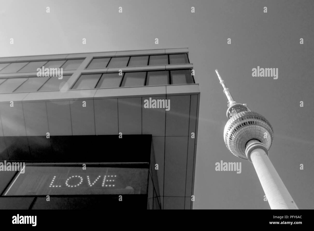 Monochrome of the Berlin TV tower (Fernsehturm) abstract next to a modern building with the word 'Love' displayed, Berlin Mitte, Germany Stock Photo