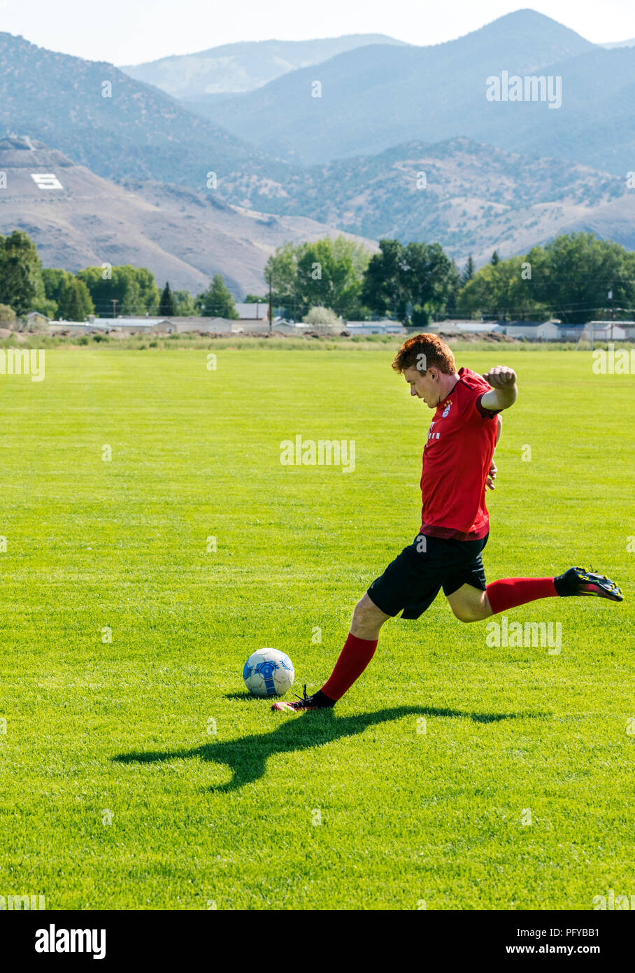 Teenage boy kicking soccer ball; playing fields; Ben Oswald Park; Salida; Colorado; USA Stock Photo