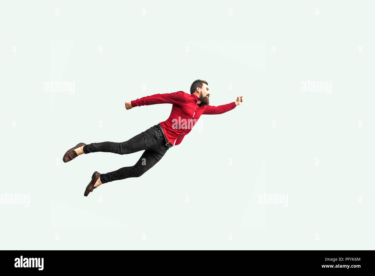 Superman style. Enthusiasm concept. strong bearded businessman felt himself a superhero and flying up. indoor studio shot isolated on gray background. Stock Photo