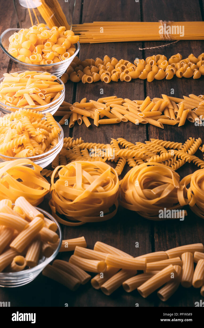 Top view of a rustic wooden table full of different types of pasta, Carbohydrates Stock Photo
