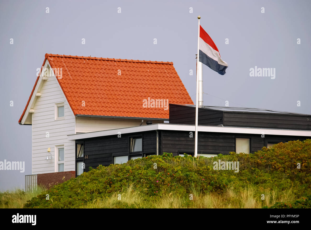 A white house and the Dutch flag on the Frisian Island of Vlieland, The Netherlands. The Frisian Islands, are also known as the Wadden Islands Stock Photo