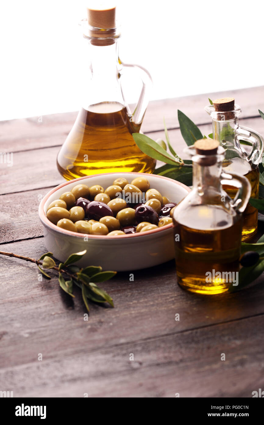 Bottle virgin olive oil and oil in a bowl with some olives Stock Photo ...