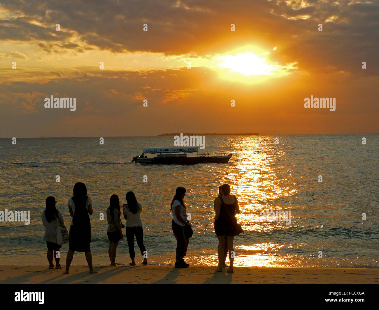 People watching the setting sun on Stone Town Beach, Zanzibar Stock Photo