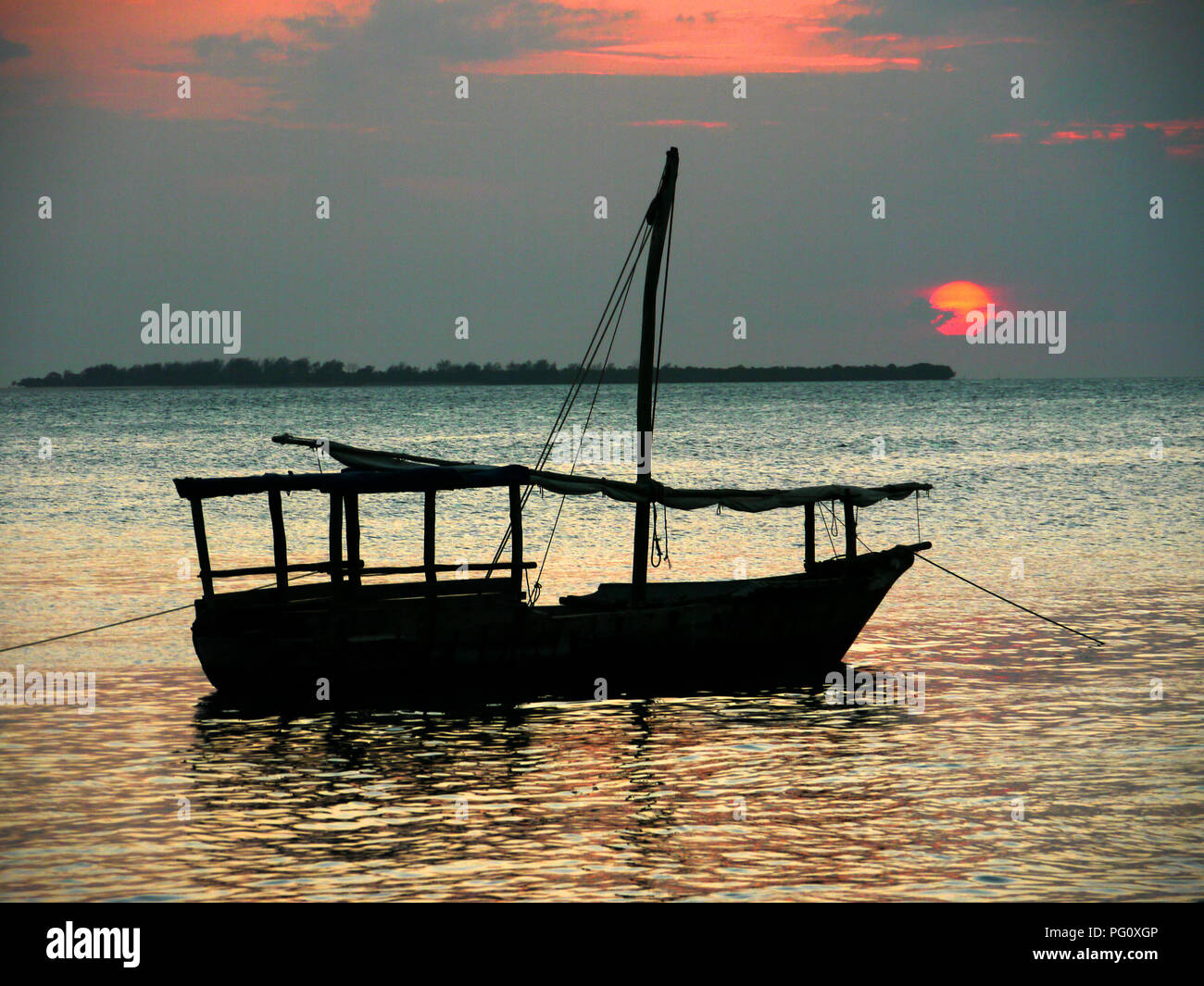 Fishing boat against the setting sun on Stone Town beach, Zanzibar, Africa Stock Photo