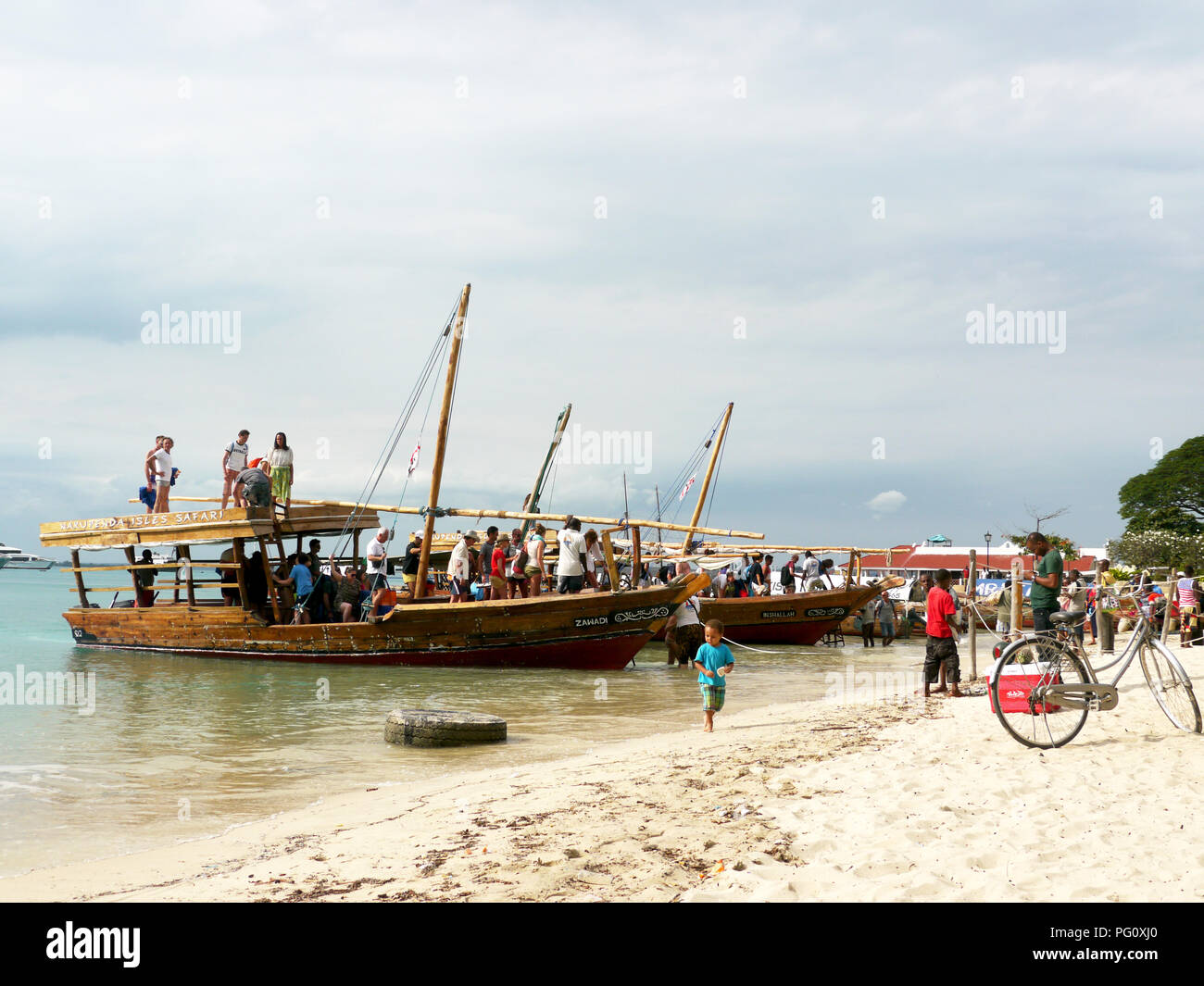 Tourists and fishing boats on the main beach or Stone Town, Zanzibar Stock Photo