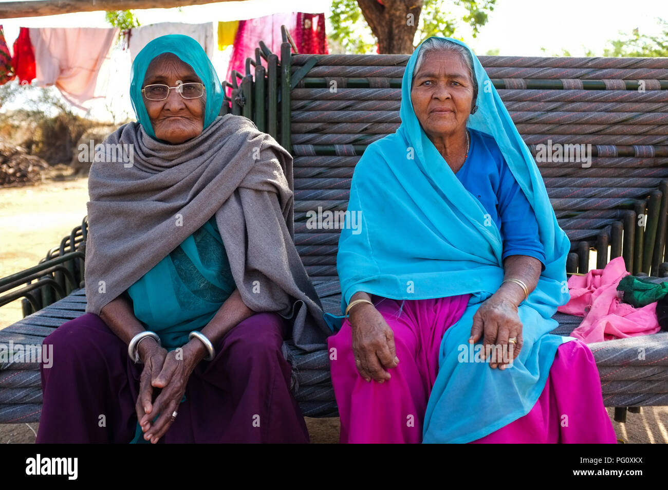 HAMPI, INDIA - FEBRUARY 14, 2015: Two elderly Indian women dressed in traditional clothes and head scarf sitting on stacked benches. Stock Photo
