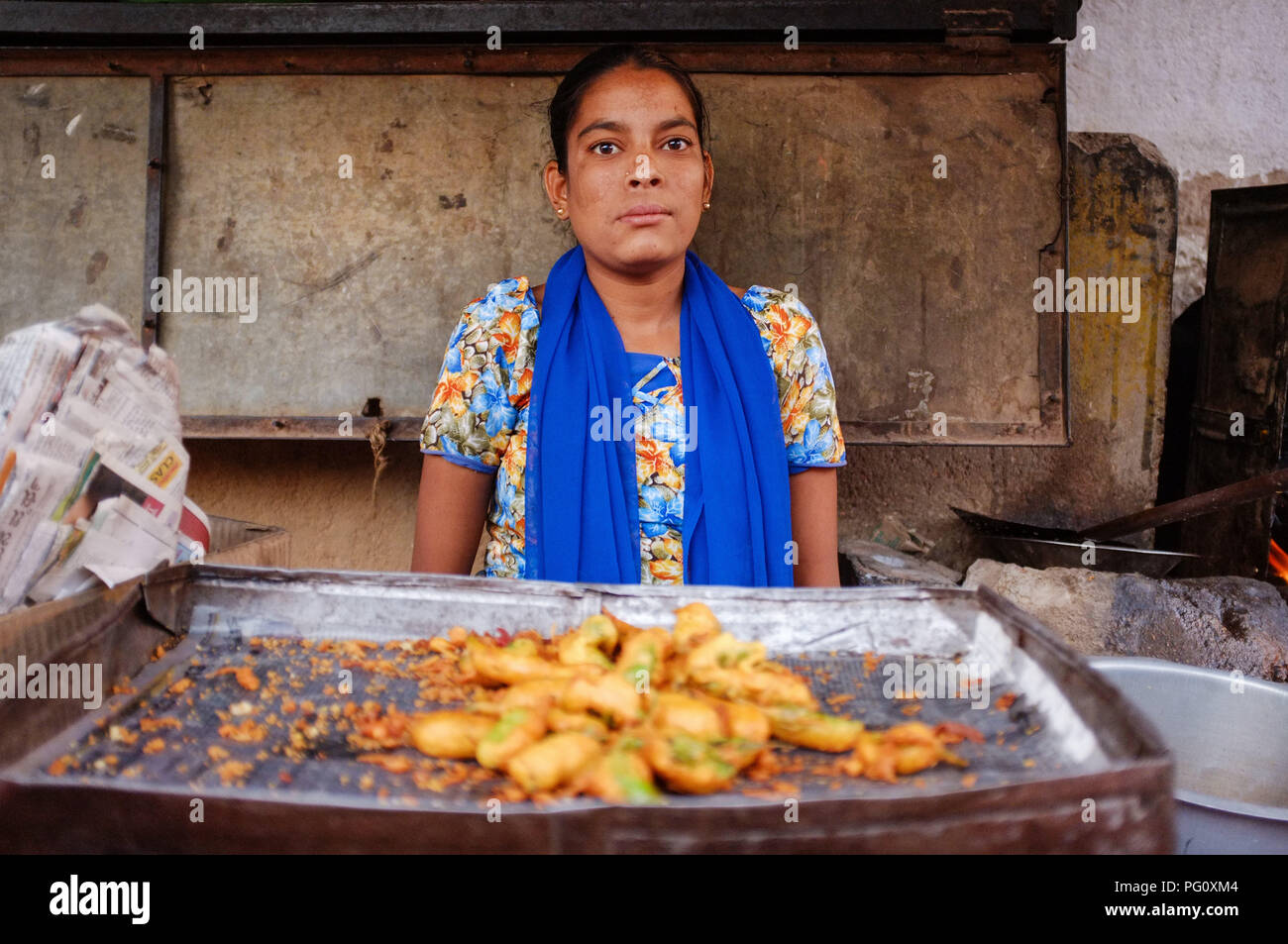 HAMPI, INDIA - JANUARY 27, 2015: Portrait of young Indian woman selling pakora on street stall in India. Stock Photo