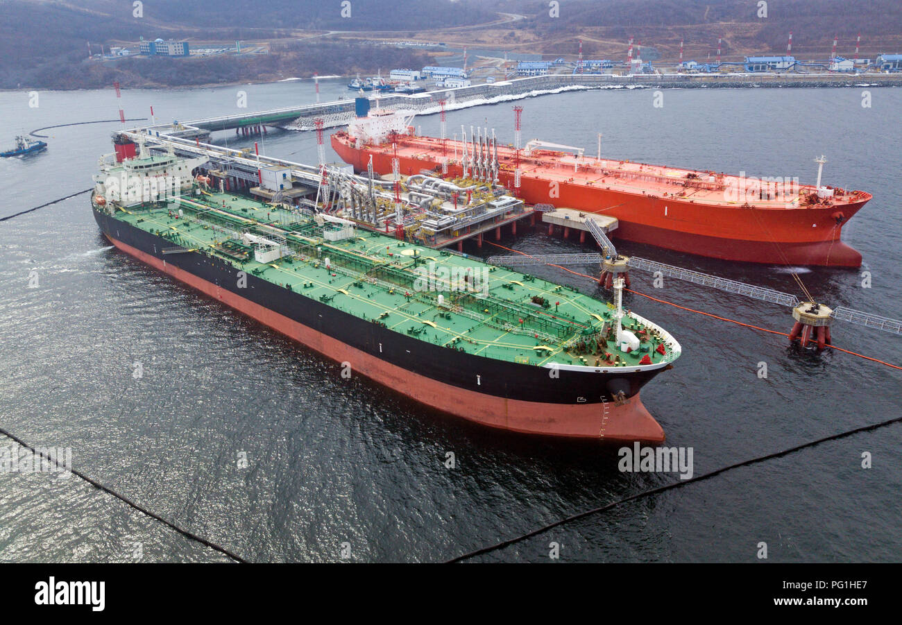 Aerial view of Oil tanker ship loading in port, Crude oil tanker ship under cargo operations on typical shore station with clearly visible mechanical  Stock Photo