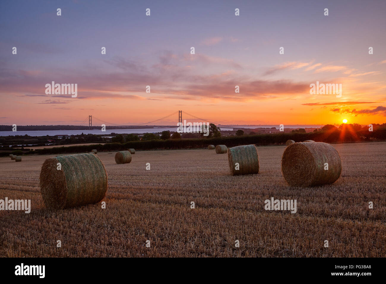Barton-upon-Humber, North Lincolnshire, UK. 24th Aug, 2018. UK Weather: Bales and the Humber Bridge at sunrise, from a stubble field outside Barton-upon-Humber. North Lincolnshire, UK. 24th Aug, 2018. Credit: LEE BEEL/Alamy Live News Stock Photo