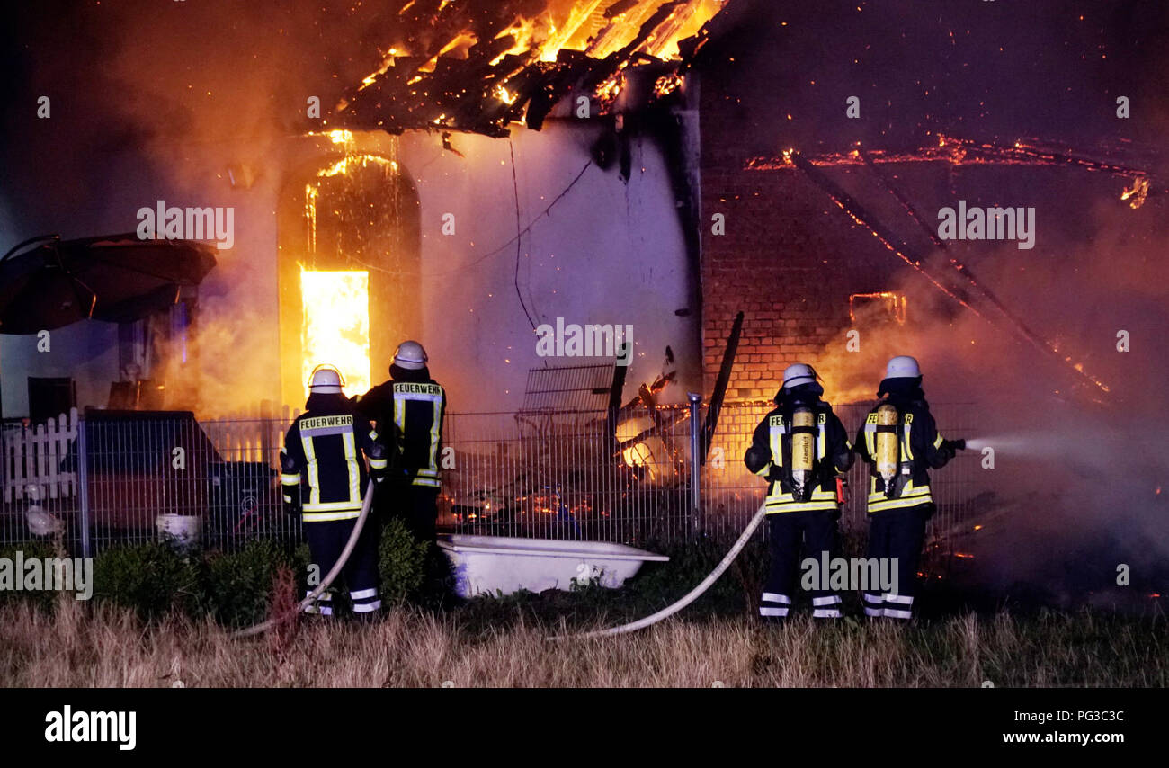 Bohmte, Germany. 24th Aug, 2018. Firefighters are fighting a fire. Several animals died in the fire at a dog farm on Friday. A police spokesman said that the fire broke out under the roof of the house in the early morning hours. The two residents were able to escape unharmed. For many of the dogs, however, any help came too late. Credit: Heinz-Juergen Reiss/NWM-TV/dpa/Alamy Live News Stock Photo