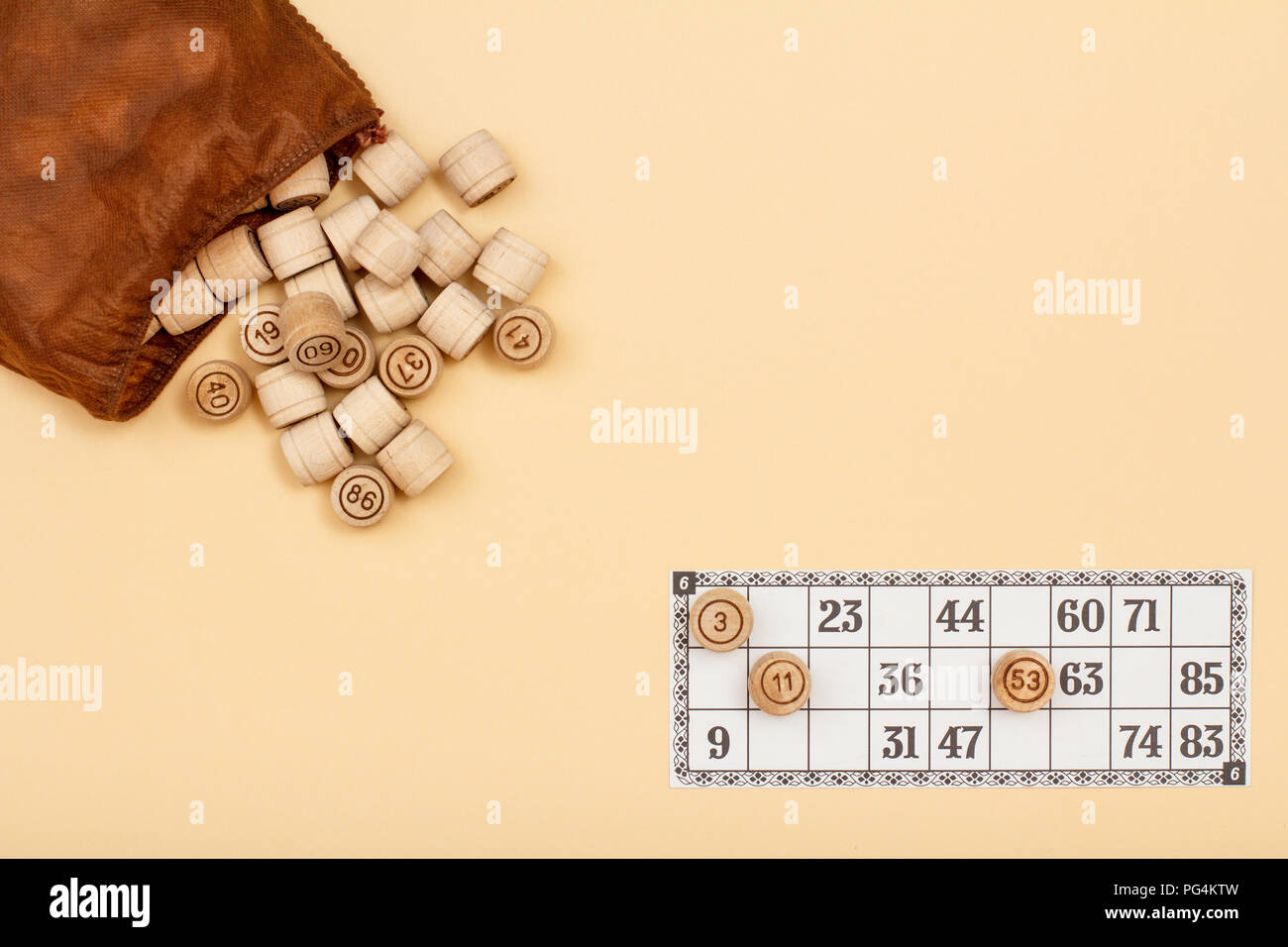 Wooden lotto barrels with brown bag and game card on beige background. Board game lotto. Top view with copy space Stock Photo