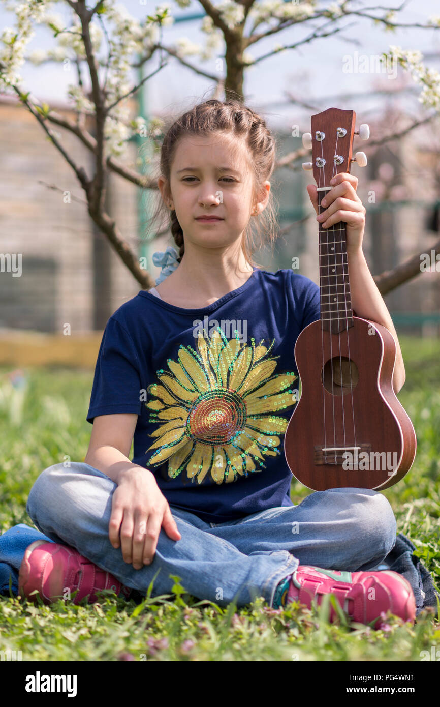 A little girl playing ukulele in the garden Stock Photo Alamy