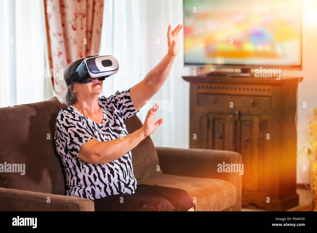 Senior woman with virtual headset or 3d glasses playing videogame at home. Technology, augmented reality, entertainment and people concept. Focus on h Stock Photo