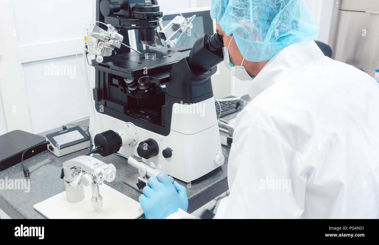 Doctor or scientist looking thru microscope in lab Stock Photo - Alamy