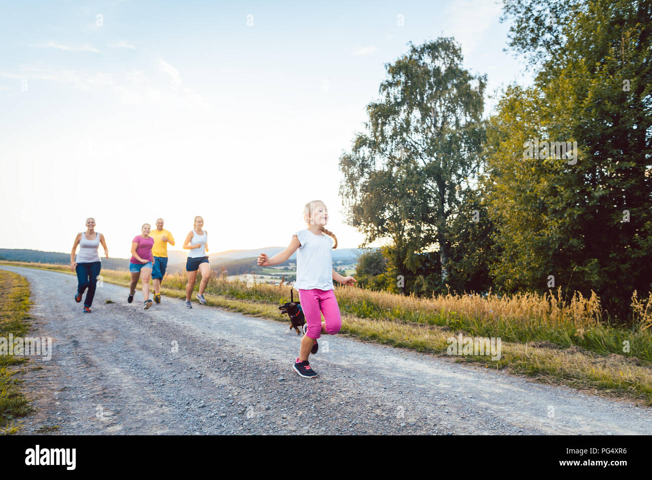 Playful family running and playing on a path in summer landscape Stock Photo
