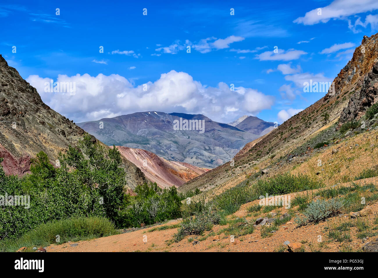 Picturesque summer mountain landscape - view from the canyon of Kyzyl Chin with multicolored clay cliffs to the Kuray Range, Altai mountains, Russia.  Stock Photo