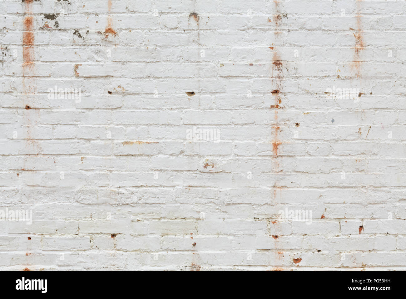 Detail of old brick wall painted white and distressed, peeling and stained. Ideal for grunge background texture Stock Photo