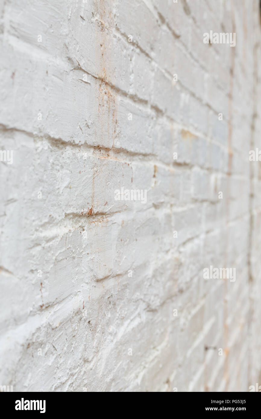 Detail of old brick wall painted white and distressed, peeling and stained. Ideal for grunge background texture Stock Photo